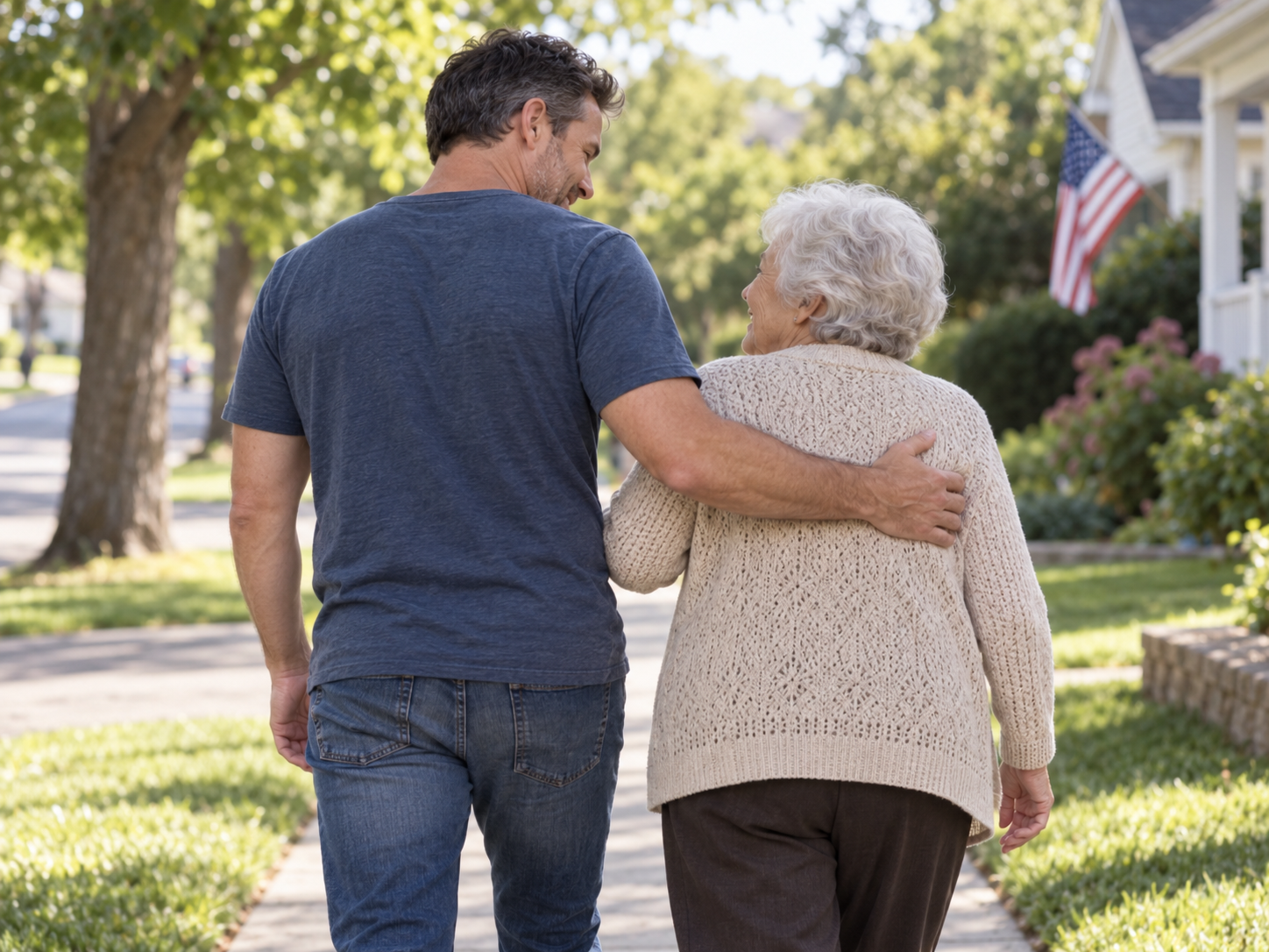 A man helping his grandmother walk along an American neighborhood street, viewed from behind